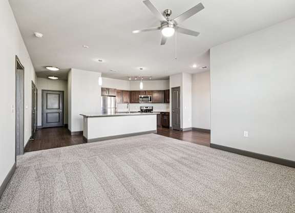 A spacious living room with a carpeted floor and a ceiling fan.at North Creek, Texas, 78634