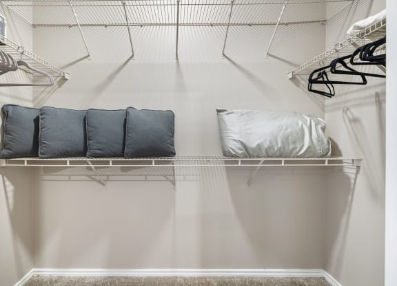 a walk in closet with white walls and shelves and a closet organizer with pillows at Sonterra Apartment Homes, Texas, 78726