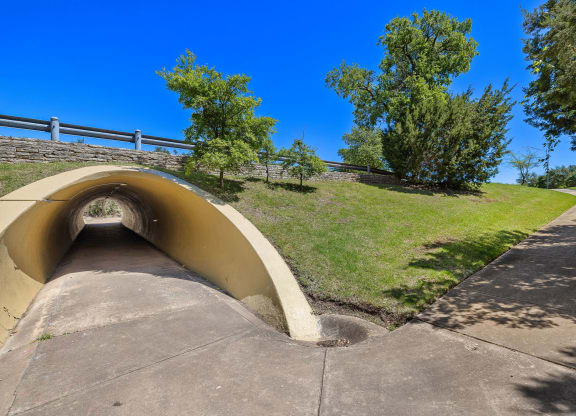 a tunnel on the side of a hill with grass and trees at Lakeline East Apartments, Cedar Park, TX