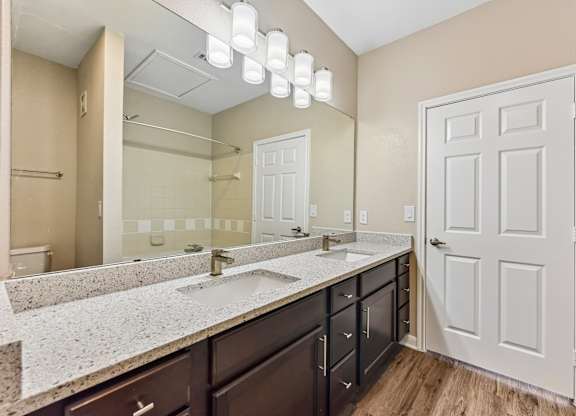 A bathroom with a sink, mirror, and wooden floors.