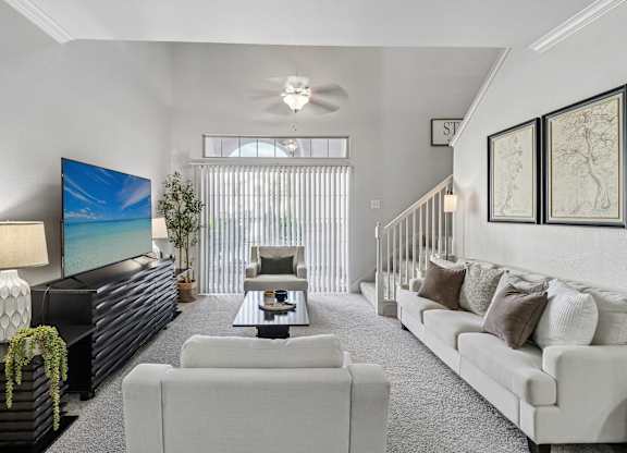 A living room with a white couch, a black coffee table, and a large painting on the wall.