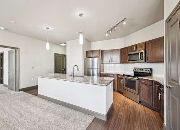 A modern kitchen with a white island and wooden cabinets.at North Creek, Texas, 78634