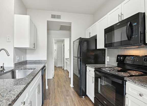 A kitchen with black appliances and white cabinets.