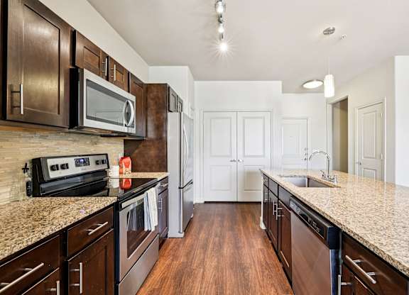 A kitchen with dark brown cabinets and granite countertops.at North Creek, Hutto, TX, 78634