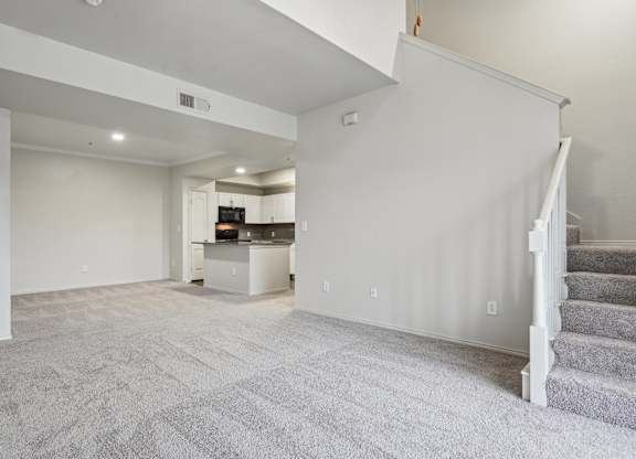 A spacious living room with a staircase on the right side.