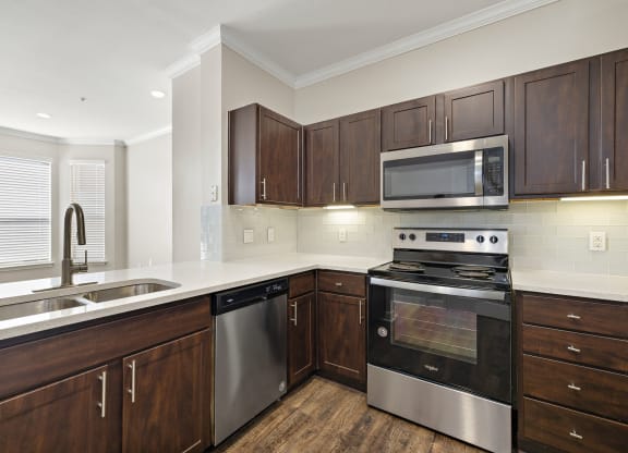 a kitchen with wooden cabinets and stainless steel appliances at The Verandah, Austin, TX