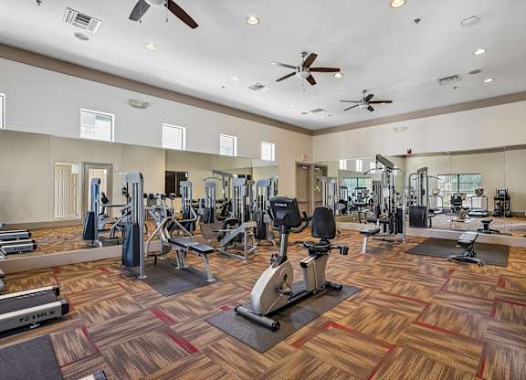 A gym with a variety of equipment including treadmills, weights, and exercise machines.