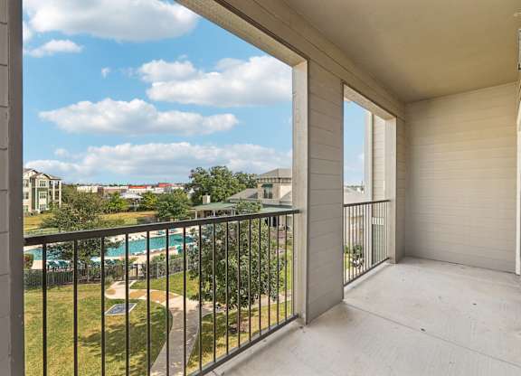 A balcony with a black railing and a pool in the distance. at North Creek, Hutto