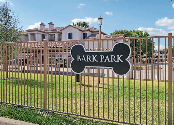 A sign that says Bark Park is on a fence.