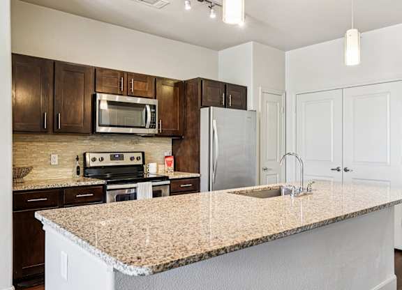 A kitchen with a granite countertop and white cabinets.at North Creek, Hutto, TX
