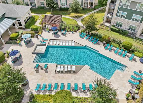 A large swimming pool surrounded by lounge chairs and umbrellas.at North Creek, Hutto, TX