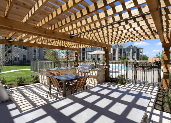 a patio with a table and chairs under a wooden pergola at North Creek, Hutto, TX