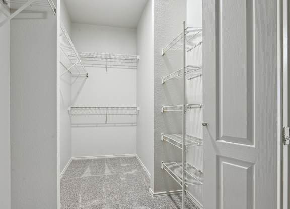A white hallway with a carpeted floor and a door on the right.