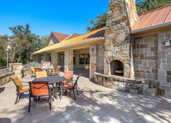 a backyard patio with a table and chairs and a stone fireplace at The Verandah, Texas, 78726