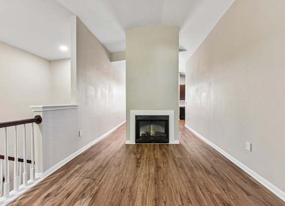 A long hallway with a fireplace and wood floors.