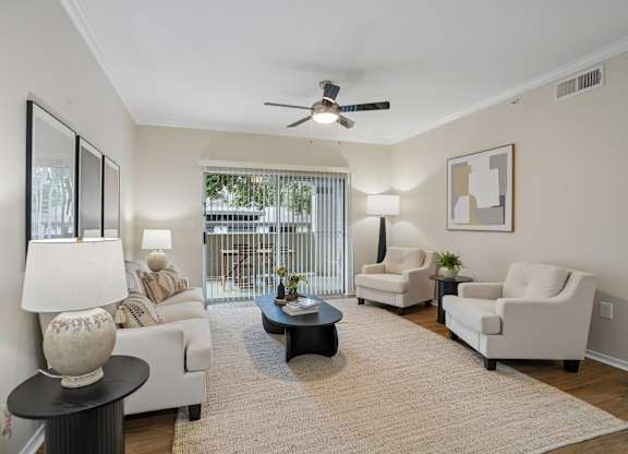 A living room with a white couch, two chairs, a coffee table, and a ceiling fan.