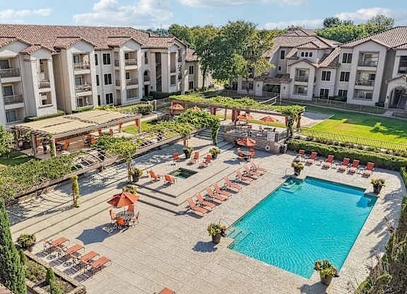 A large swimming pool surrounded by red lounge chairs and umbrellas.