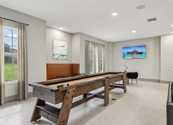 A pool table in a room with a television on the wall.