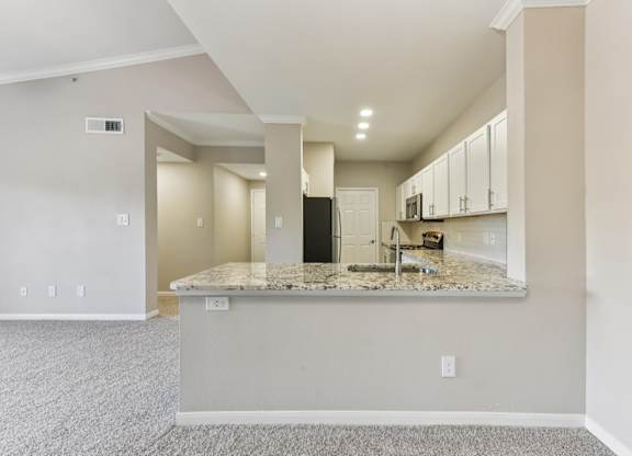 A kitchen area with a granite countertop and white cabinets. at Sonterra Apartment Homes, Austin