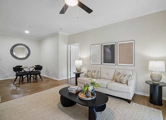 A living room with a white couch, a black coffee table, and a round mirror on the wall.