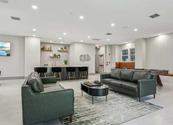 A living room with a green couch, a black coffee table, and a television.