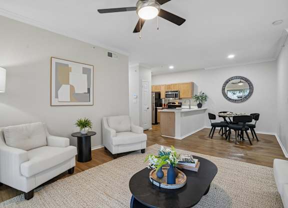 A living room with a white sofa, a black coffee table, and a ceiling fan.