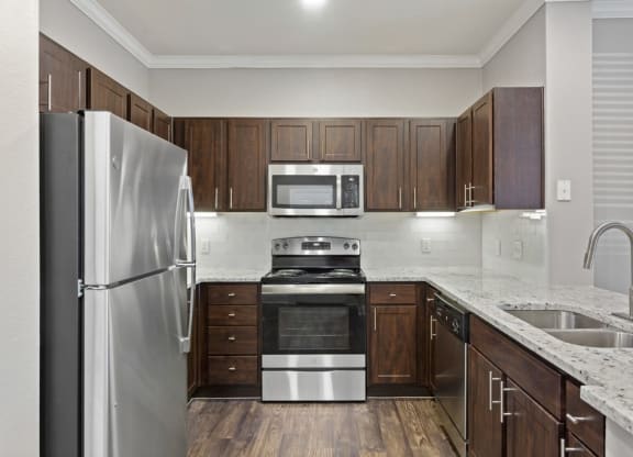 a kitchen with dark wood cabinets and stainless steel appliances at The Verandah, Austin, Texas