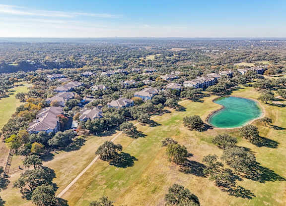 A bird's eye view of a residential area with houses and a lake at Legends on the Green Apartments, San Antonio, TX