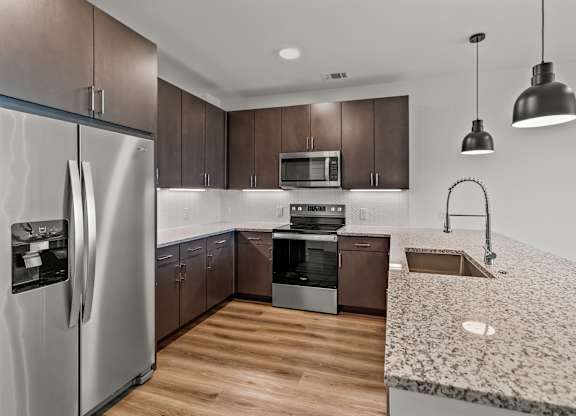 A modern kitchen with a refrigerator, microwave, oven, sink, and dishwasher. at Aurora Watson Branch, Texas, 76063
