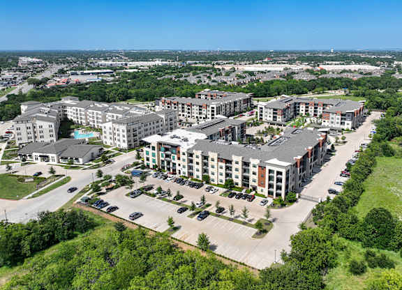 A bird's eye view of a large apartment complex surrounded by greenery and roads. at Aurora Watson Branch, Texas