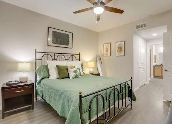 A bedroom with a bed, nightstand, and a ceiling fan.