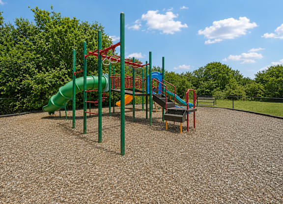 A playground with a green slide and red and green play structures.