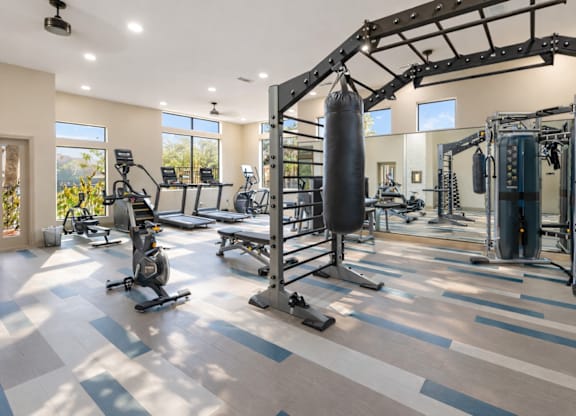 A spacious gym with a variety of equipment including a punching bag, weight machines, and a squat rack.