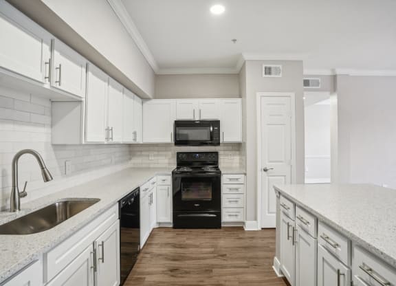 a white kitchen with white cabinets and a black stove and oven  at The Verandah, Austin, 78726