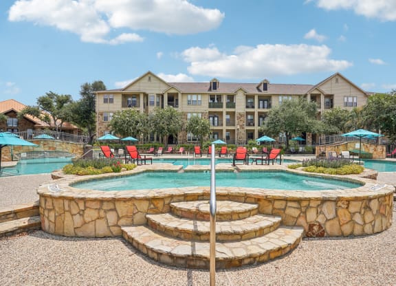 a swimming pool with a fountain and a hotel in the background at The Verandah, Austin, TX, 78726