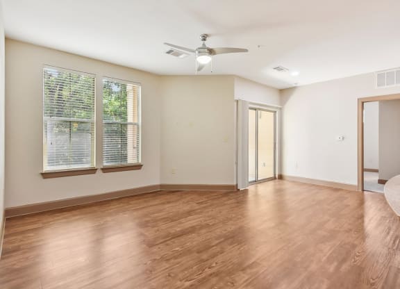 an empty living room with wood floors and a ceiling fan at Lakeline East Apartments, Texas, 78613