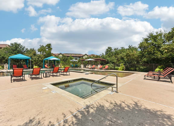 the reserve at the falls pool and hot tub with chairs and umbrellas at Lakeline East Apartments, Cedar Park