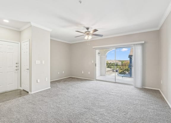 an empty living room with a ceiling fan and a window