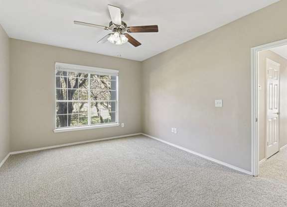 an empty bedroom with a ceiling fan and a window