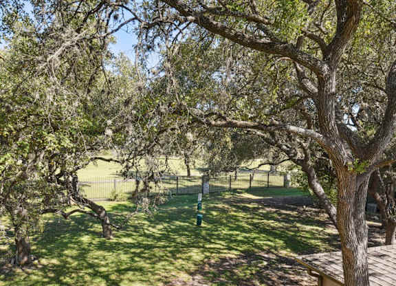 a view of a park with trees and a fence