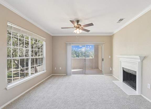an empty living room with a fireplace and a ceiling fan