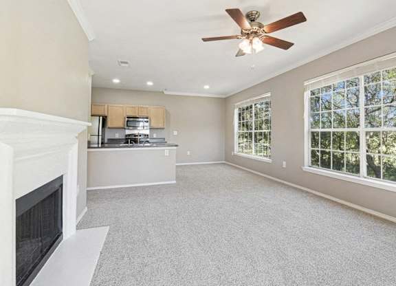 an empty living room with a fireplace and a ceiling fan
