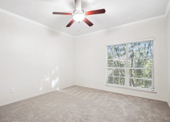 an empty living room with a ceiling fan and a window at La Ventura Apartments, Plano, 75093