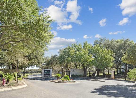 the entrance to a park with trees and a street
