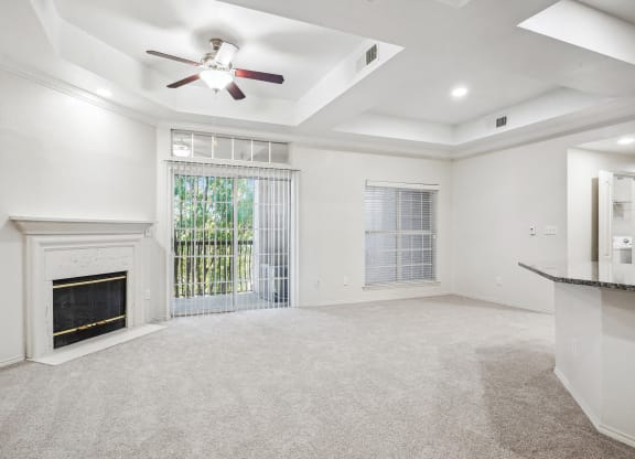 an empty living room with a fireplace and a ceiling fan at La Ventura Apartments, Plano, 75093