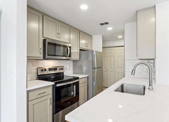a white kitchen with stainless steel appliances and white counter tops at The Legends at Eagle Mountain Lake, Fort Worth, Texas
