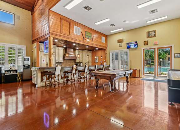 A large room with a wooden floor and a bar area. at The Canyons Apartments, Fort Worth