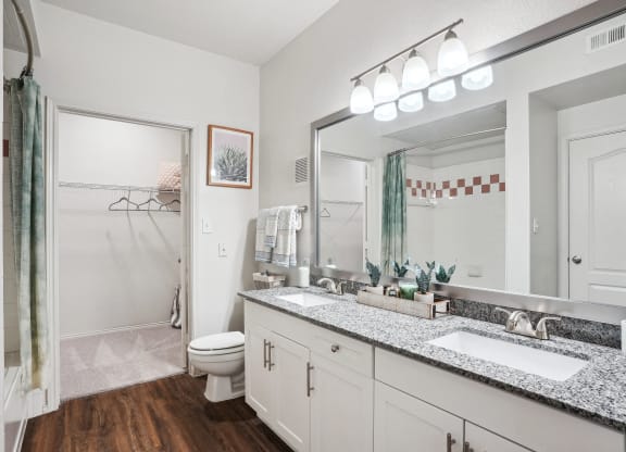 a bathroom with a large mirror and a sink and a toilet at La Ventura Apartments, Plano, Texas