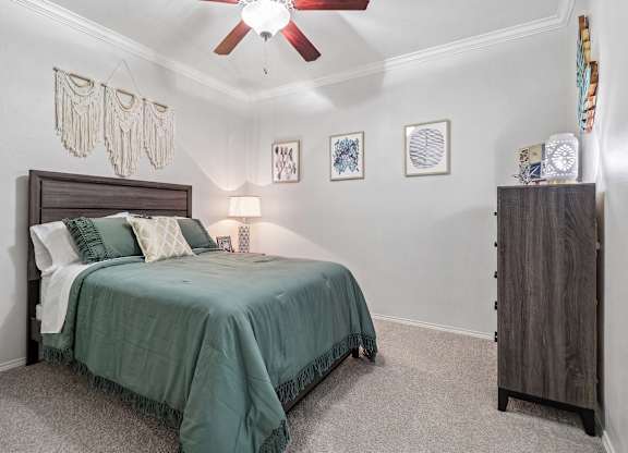 A bedroom with a bed, a ceiling fan, and a wooden cabinet.