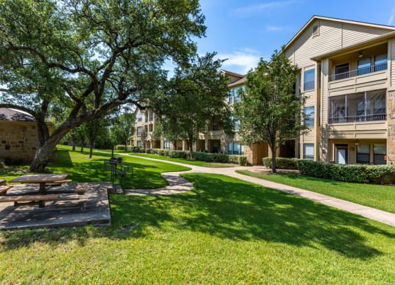 a picnic area with a table and benches in front of an apartment building at The Verandah, Austin, TX, 78726